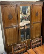 An Edwardian mahogany three door wardrobe with a central mirrored door on square legs together