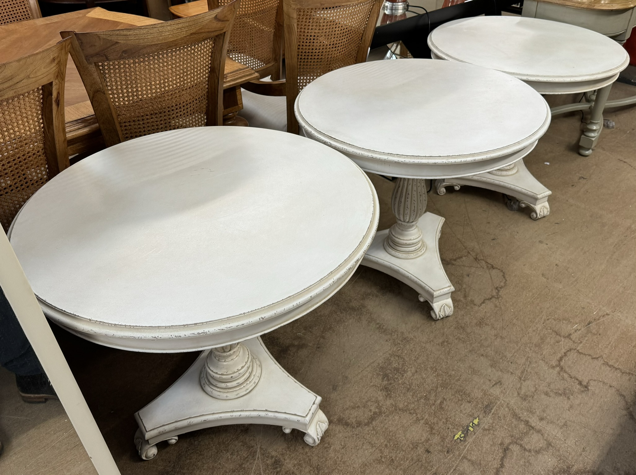 A set of three cream painted occasional tables on ribbed columns and a trefoil base and leaf carved