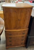 A yew drinks cabinet with a pair of cupboard doors above a slide,