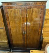 An Edwardian mahogany wardrobe with a moulded cornice above a pair of cupboard doors on bracket