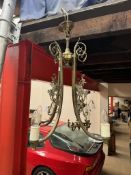 A brass three branch chandelier with scrolling leaves and dragon castings