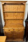A pine dresser with a moulded cornice above two shelves,