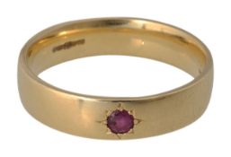 An 18ct gold band with a gypsy set ruby stone