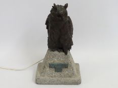 A bronze owl with back lit glass eyes set on a rec