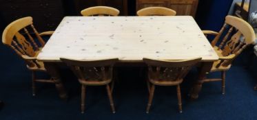 A stripped pine farmhouse kitchen table with two c