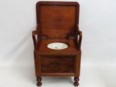 A 19thC. mahogany commode with fold down arm rests