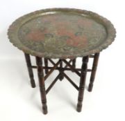A Benares metal table with folding stand, 530mm hi