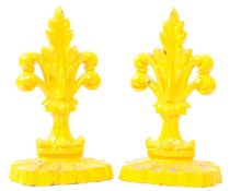 TWO 20TH CENTURY YELLOW CAST METAL FLEUR DE LIS DOORSTOPS