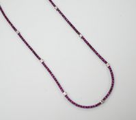 A modern blackened 18k, ruby and diamond line cluster set necklace, 42cm, gross weight 10.3 grams.
