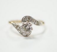 An 18ct, plat and single stone diamond set ring, with diamond chip set crossover shoulders, size P/