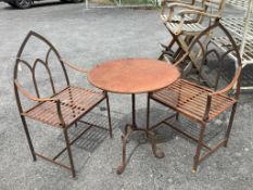 A weathered wrought iron circular garden table, diameter 60cm, height 76cm, together with a pair