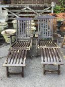 A pair of stained teak garden steamer chairs. Condition - fair