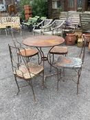 An early 20th century wrought iron garden table, diameter 70cm, height 75cm and four chairs.