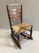 A 19th century ash rush seat ladderback rocking chair, width 48cm, depth 37cm, height 85cm.