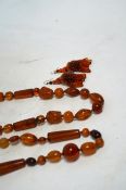 Two amber bead necklaces including Chinese with carved busts, 76cm and a pair of drop earrings,