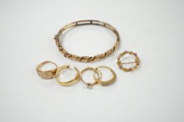 An early 20th century 9ct hinged bangle, three assorted 9ct gold rings and a modern 9ct gold and gem