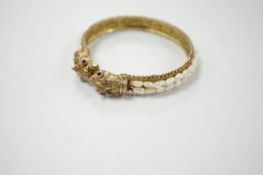 A Chinese? gilt white metal and freshwater pearl cluster set hinged bangle, with red stone eyes.