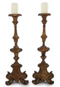 A pair of 18th century Italian giltwood candlesticks with knopped triangular stems and scroll