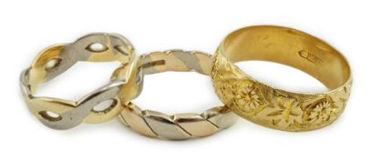 A George V engraved 18ct gold band, size M/N, together with two three or two colour 18ct gold bands,