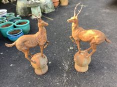 A pair of cast iron finials as deer standing upon spheres, height 92cm. Condition - weathered