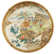 A Japanese Satsuma ‘garden scene’ dish, Meiji period, painted with figures in a landscape to a fan