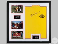 A yellow commemorative football shirt signed by Gordon Banks