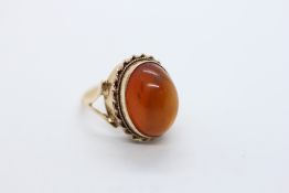 AN ELABORATE 9CT GOLD RING SET WITH AN OVAL AMBER PANEL.