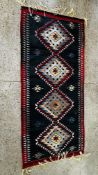 A PERSIAN FLAT WEAVE RUG WITH LOZENGE MOTIFS ON A DARK BLUE FIELD.