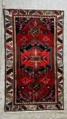 A CAUCASIAN RUG THE CENTRAL MOTIF ON AN OF RED FIELD, CUP AND LEAF GUARD STRIPE.