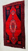 A PERSIAN RUG, THE CRUCIFORM MOTIF ON A RED FIELD.