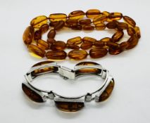 A STRING OF GRADUATED AMBER BEADS ALONG WITH A MODERN DESIGNER SILVER BRACELET SET WITH AMBER
