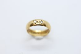 AN 18CT GOLD BAND RING SET WITH TWO SMALL DIAMONDS IN STARBURST SETTING, SIZE N/O.
