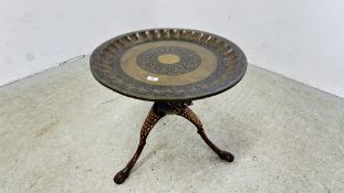 AN INDIAN STYLE BRASS TOP OCCASIONAL TABLE SUPPORTED ON A FOLDING TRIPOD BASE - DIAM 58.5CM H 50CM.