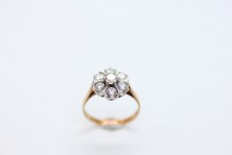 A 9CT GOLD RING, THE SEVEN CZ STONES IN A FLOWER HEAD DESIGN.