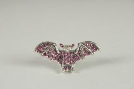 A SILVER RUBY, DIAMOND BAT BROOCH.