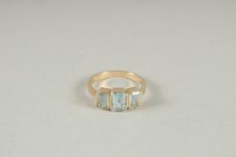 A 9CT GOLD THREE STONE EMERALD CUT BLUE TOPAZ RING.