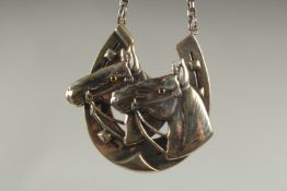 A heavy silver horses head and shoe necklace and chain in a box.