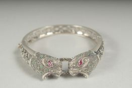 A silver ruby and emerald panther bangle in a box.