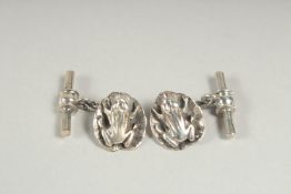 A pair of silver frog on a lily pad cufflinks in a box.