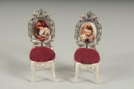 A SMALL PAIR OF SILVER AND ENAMEL PIN CUSHION CHAIRS.