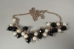 A silver chain pearl onyx and bead necklace in a box.