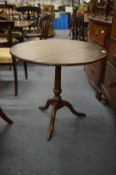 An oak tilt-top circular tripod table.