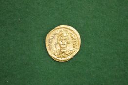 A gold coin, possibly a Byzantine Solidus together with two other coins.