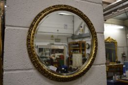 A gilt framed circular wall mirror.