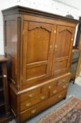 A George III oak linen press with a pair of panel doors above dummy drawers and three real