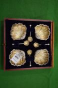 A set of four shell shaped salts with matching spoons.