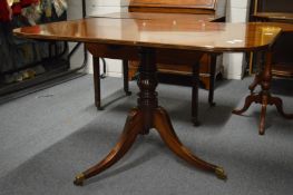 A mahogany tilt-top pedestal dining table with rounded rectangular top, turned column support on