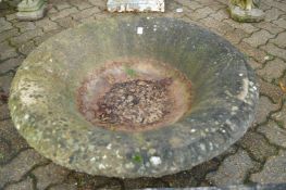 A large circular reconstituted stone garden planter (lacking base).