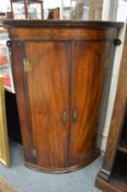 A George III mahogany bow front hanging corner cupboard.