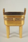 A CHINESE HEAVY GILDED BRONZE TWIN HANDLE CENSER, raised on four tall legs, the base with